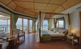 a bedroom with a large bed and canopy , wooden floors , and a view of the ocean at Safari Island