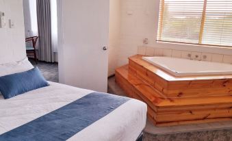 a bedroom with a blue and white striped bed , a bathtub in the corner , and a window at Bremer Bay Resort