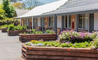 a row of wooden planters filled with flowers in front of a building , creating a beautiful and inviting atmosphere at Maffra Motor Inn