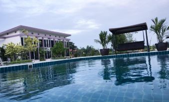 a large swimming pool surrounded by a hotel , with several people enjoying their time in the pool area at Menam Resort