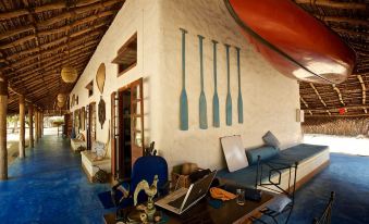 a room with a laptop on a table , surrounded by chairs and a wooden wall with six paddles painted on it at Dolphin Beach Resort