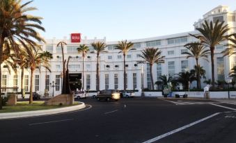 a large white building with palm trees in front of it and cars parked in front at Hotel Riu Palace Oasis