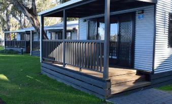 a wooden deck with a railing and a covered area is situated in front of a house at Cohuna Waterfront Holiday Park