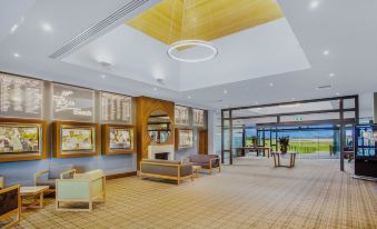 a modern hotel lobby with wooden flooring , multiple seating areas , and a view of the ocean at 13th Beach Golf Lodges