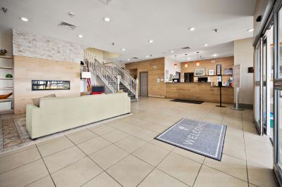 a hotel lobby with a staircase leading to the second floor , a reception desk , and several chairs at Country Inn & Suites by Radisson, Watertown, SD