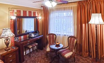 a cozy living room with red curtains , a large window , and two armchairs , as well as a dining table in the corner at Riverside Inn