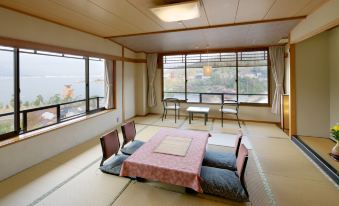 a large , empty room with a tatami mat floor and a view of the ocean at Jukeiso