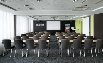 a conference room with rows of chairs arranged in front of a projector screen , ready for a meeting or presentation at Park Inn by Radisson Central Tallinn