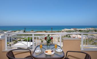 a table with a breakfast setting on it , overlooking the ocean and a clear blue sky at Sunrise Apartments