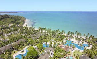 aerial view of a tropical resort with palm trees , a beach , and a pool , surrounded by clear blue water at Robinson Khao Lak