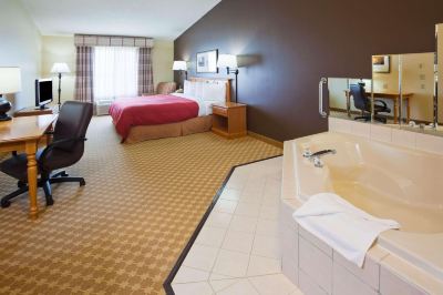 a hotel room with a bed , desk , chair , and a bathroom with a bathtub at Country Inn & Suites by Radisson, Watertown, SD