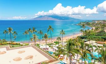 a beautiful beach resort with palm trees , a swimming pool , and a view of the ocean at Four Seasons Resort Maui at Wailea