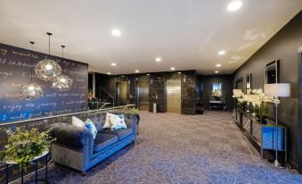 a modern living room with blue couches , a marble floor , and a chandelier hanging from the ceiling at Mantra Albury Hotel