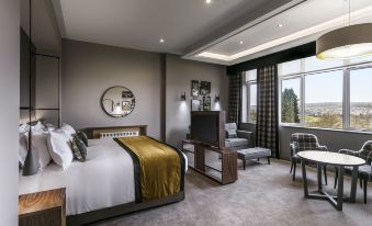 a modern hotel room with a large bed , white walls , and a view of the city at Castle Green Hotel in Kendal, BW Premier Collection