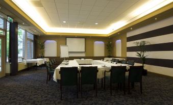 a conference room set up for a meeting , with chairs arranged in a semicircle around a table at Fletcher Parkhotel Val Monte