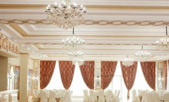 a large , elegant banquet hall with white walls and ceiling , multiple chandeliers , and red curtains , as well as white drapes on at "Palazzo"