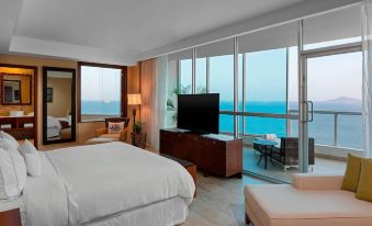 a luxurious hotel room with a large window offering a view of the ocean , white bedding , and a flat - screen tv at The Westin Playa Bonita Panama