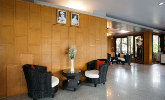 a modern , minimalist living room with wooden walls and large windows , featuring comfortable black wicker furniture and a vase of flowers at Diamond Park Inn Chiangrai & Resort