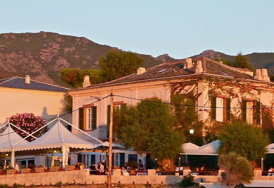 a large white building surrounded by trees and mountains , with a tent set up in front of it at Hotel-Restaurant le Vieux Moulin