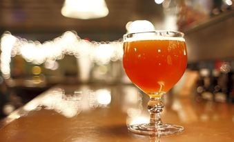 a glass of beer is placed on a wooden table , with the background blurred and blurred at Hotel Miami