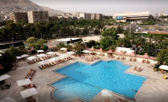 a large outdoor swimming pool surrounded by lounge chairs and umbrellas , providing a relaxing atmosphere at Sheraton Hotel