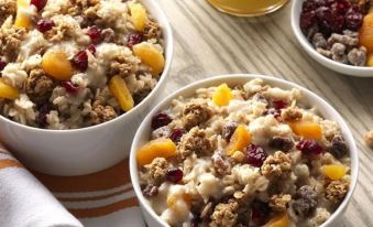 two white bowls filled with a variety of fruits and granola , placed on a dining table at Home2 Suites by Hilton Williamsville Buffalo Airport