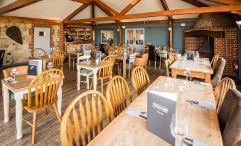 a large , empty restaurant with wooden tables and chairs , as well as a fireplace in the background at The Chequers Inn