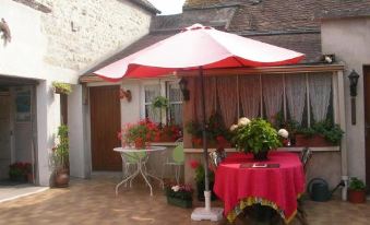 a small house with a red and white awning , a table with flowers , and an umbrella at Le 5
