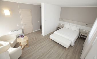 a white bedroom with hardwood floors , a large bed , and a dining table in the room at Hotel Europa