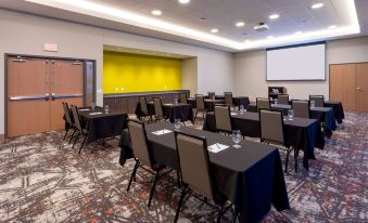 a conference room with several tables and chairs arranged for a meeting , along with a projector screen and a whiteboard at Running Aces Hotel & Casino Trademark Collection by Wyndham