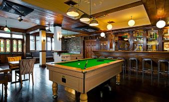 a well - lit bar area with a pool table in the center , surrounded by chairs and couches at Shannon Springs Hotel