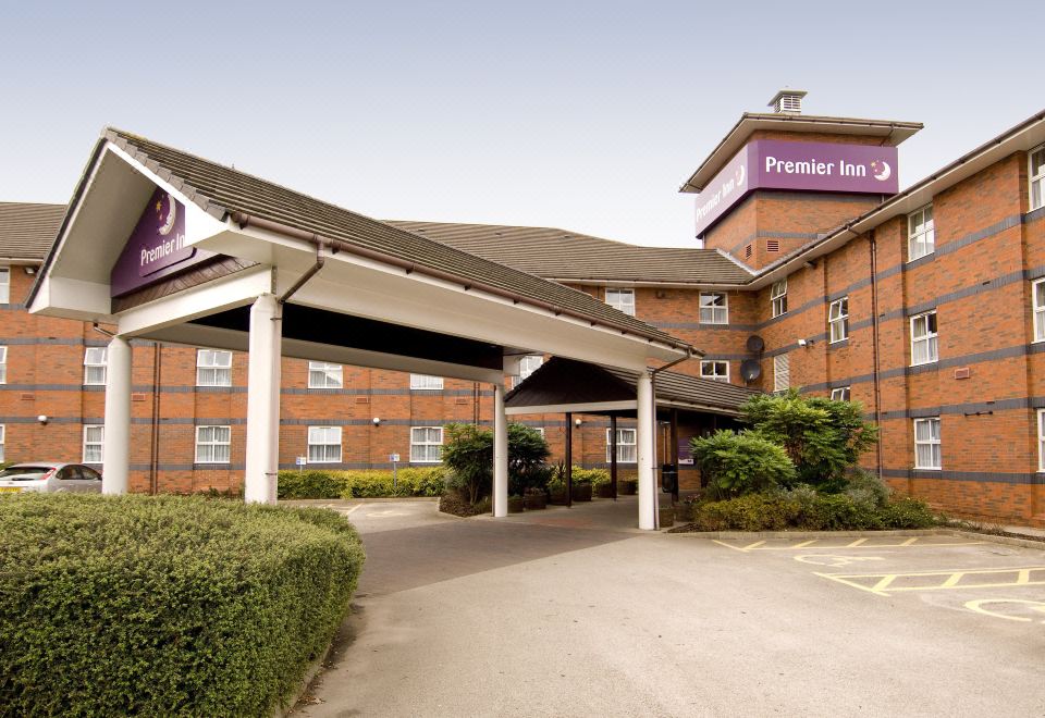 an exterior view of a hotel or motel , featuring a large entrance and a sign above it at Premier Inn Derby East