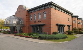 a large , red brick building with a domed roof and arched windows is surrounded by greenery at The Clarkson Inn