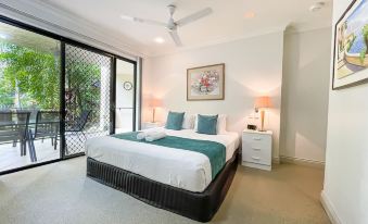 a spacious bedroom with a king - sized bed , two nightstands , and a large window overlooking a beautiful garden at Trinity Links Resort