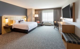 a modern hotel room with a large bed , desk , and couch , along with a tv and other amenities at Running Aces Hotel & Casino Trademark Collection by Wyndham