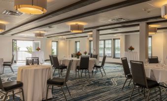 a large , well - lit conference room with multiple tables and chairs set up for an event at Hotel Canandaigua, Tapestry Collection by Hilton