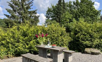 a stone table and benches set up in a garden , surrounded by greenery and trees at Hartmann