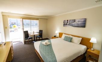 a hotel room with a comfortable bed , a dining table , and a window overlooking the ocean at Hospitality Esperance, SureStay Collection by Best Western