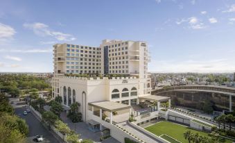 a large white building with a rooftop garden and a green lawn in front of it at Hyatt Centric Janakpuri New Delhi