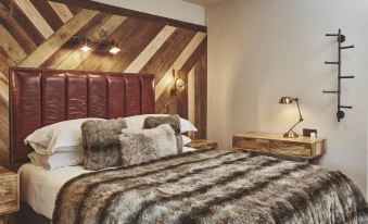 a bed with a wooden headboard and furry blankets is shown in a room with red walls at The Garrison