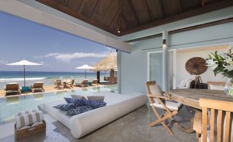 a bedroom with a large window overlooking the ocean and a couch in the foreground at Naladhu Private Island