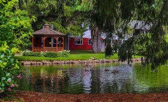 a red house with a wooden gazebo is situated on the shore of a lake at Woodwards White Mountain Resort, BW Signature Collection