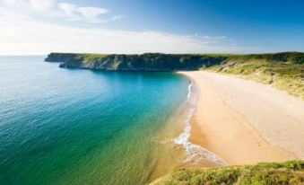 a beautiful beach scene with a sandy shoreline and a large body of water in the background at Parsonage Farm Inn