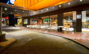 a large outdoor dining area with tables and chairs , situated next to a building with orange lighting at Hotel America Igualada