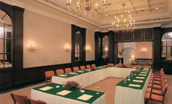 a conference room set up for a meeting , with tables and chairs arranged in rows at The Oberoi Grand Kolkata