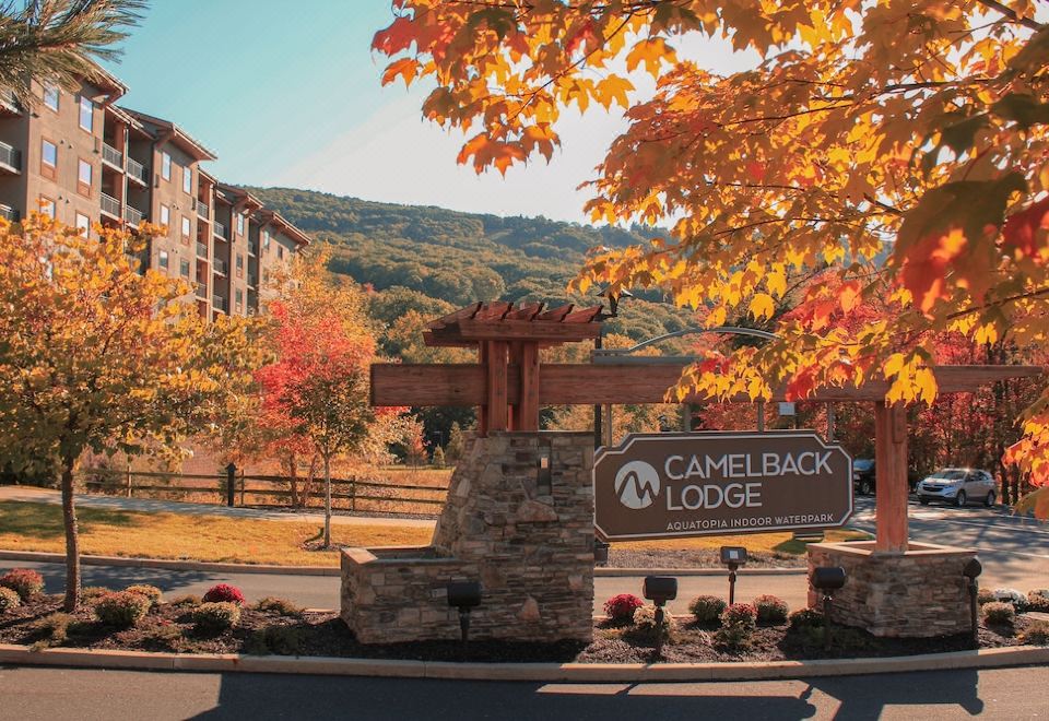 a large stone sign for camelback lodge , surrounded by autumn trees and mountains in the background at Camelback Lodge & Aquatopia Indoor Waterpark