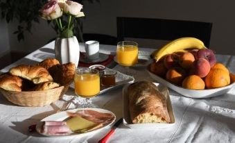 a dining table with a breakfast spread , including various types of food and beverages , including coffee , juice , and bread at Le Cercle Chambres Climatisees