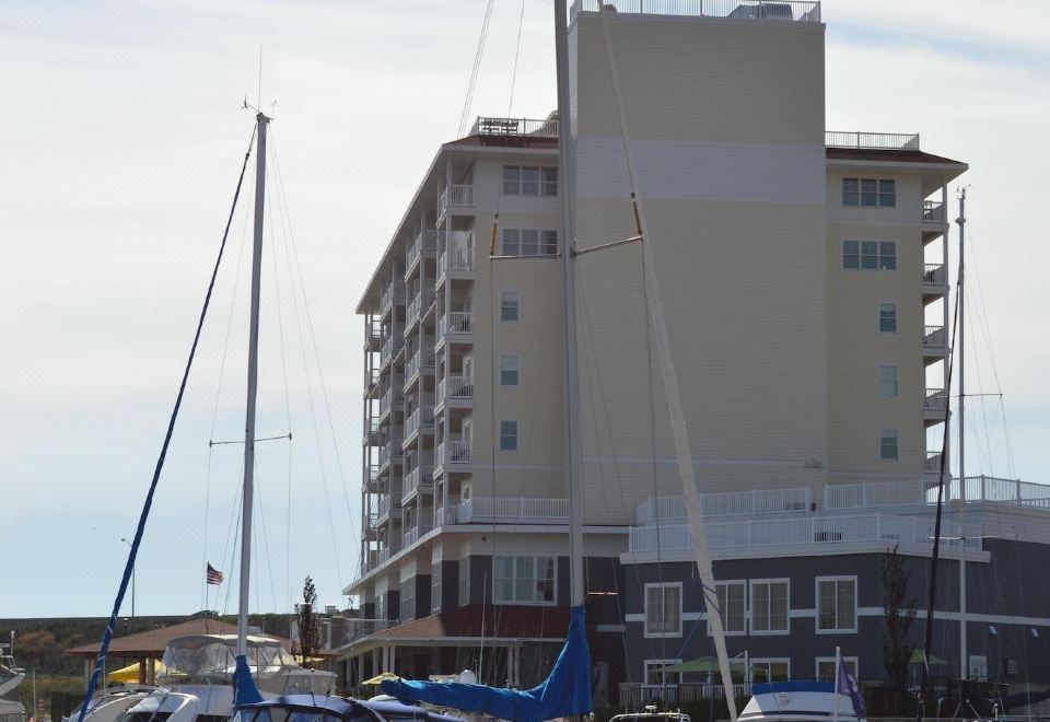 a marina with several boats docked , including a sailboat and a catamaran , in front of a tall building at The Inn at Harbor Shores