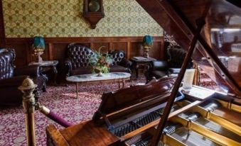 a room with a piano in the corner , surrounded by chairs and a couch , and decorated with flowers at Grand Imperial Hotel