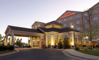 a large hotel with a parking lot in front of it , lit up at dusk at Hilton Garden Inn Laramie